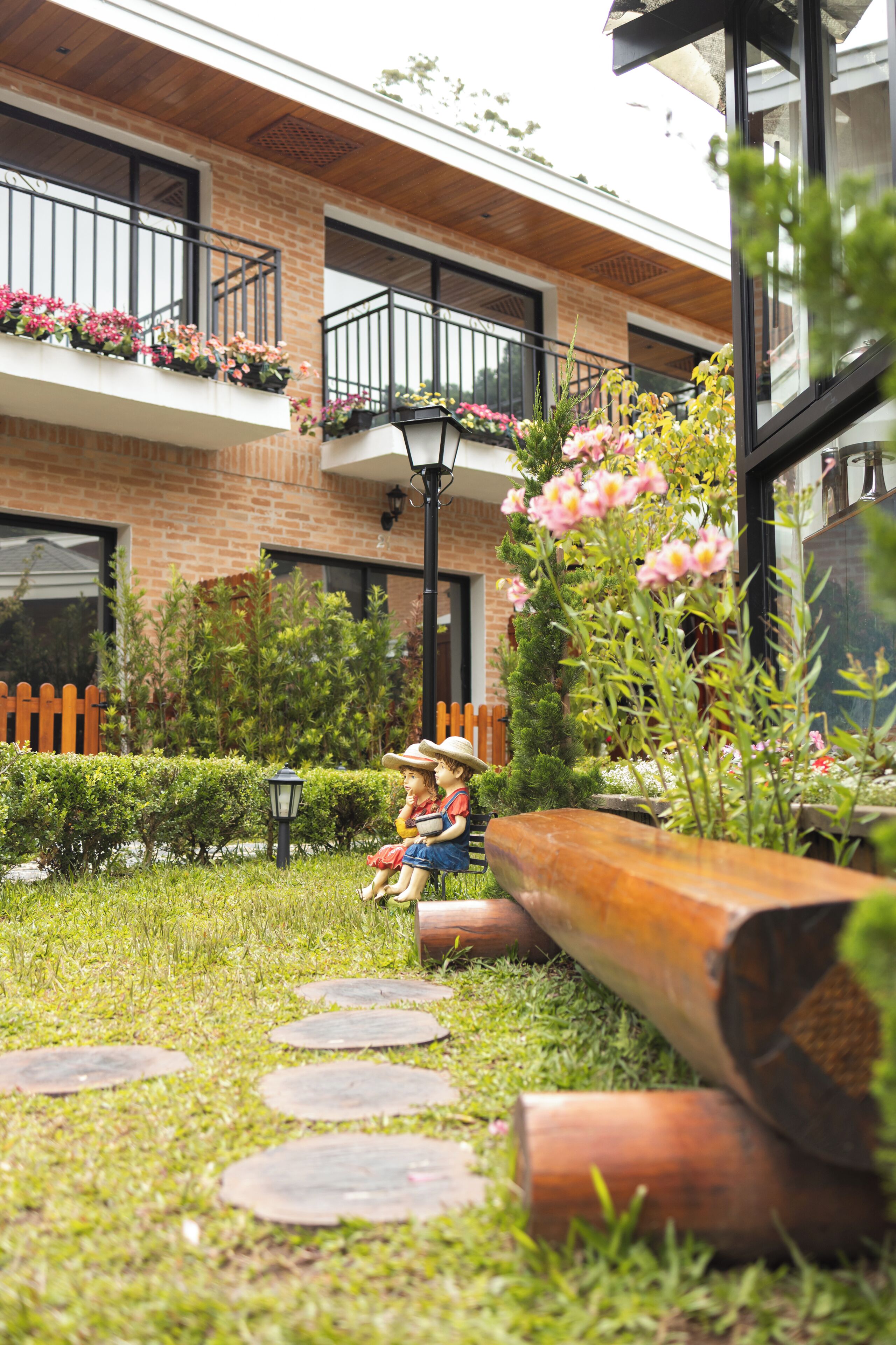 A courtyard with a brick building, a wooden bench, and a statue of two children.