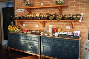 Disposição de buffet com diversos alimentos e bebidas em prateleiras e balcão.