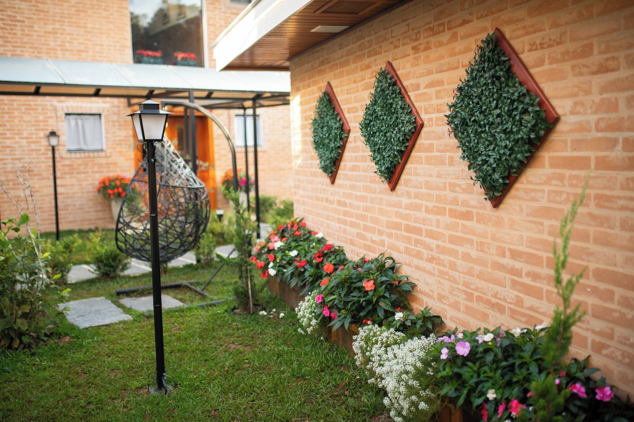 Ein Backsteinhaus mit Gartenanlage, einem hängenden Pflanzgefäß und einem dekorativen Wandbehälter.
