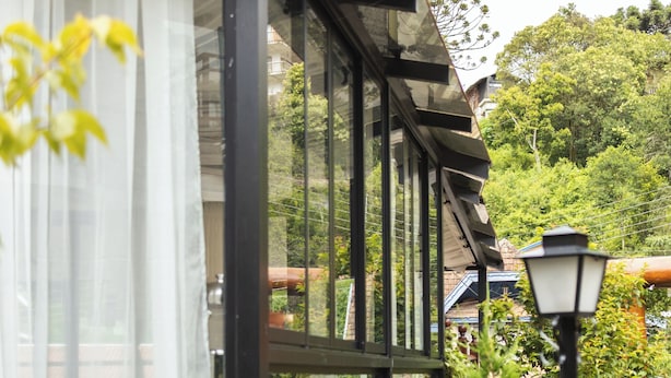 Ett vinterträdgård med utsikt över en trädgård och en byggnad i bakgrunden.
