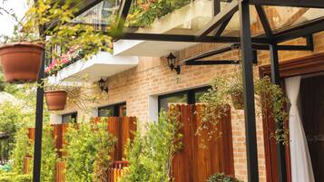 Un espacio al aire libre cubierto, con pared de ladrillo, plantas en macetas y cerca de madera.