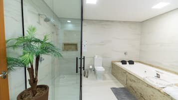 A modern bathroom with a glass-enclosed shower, a toilet, a sink with a countertop, and a potted plant.