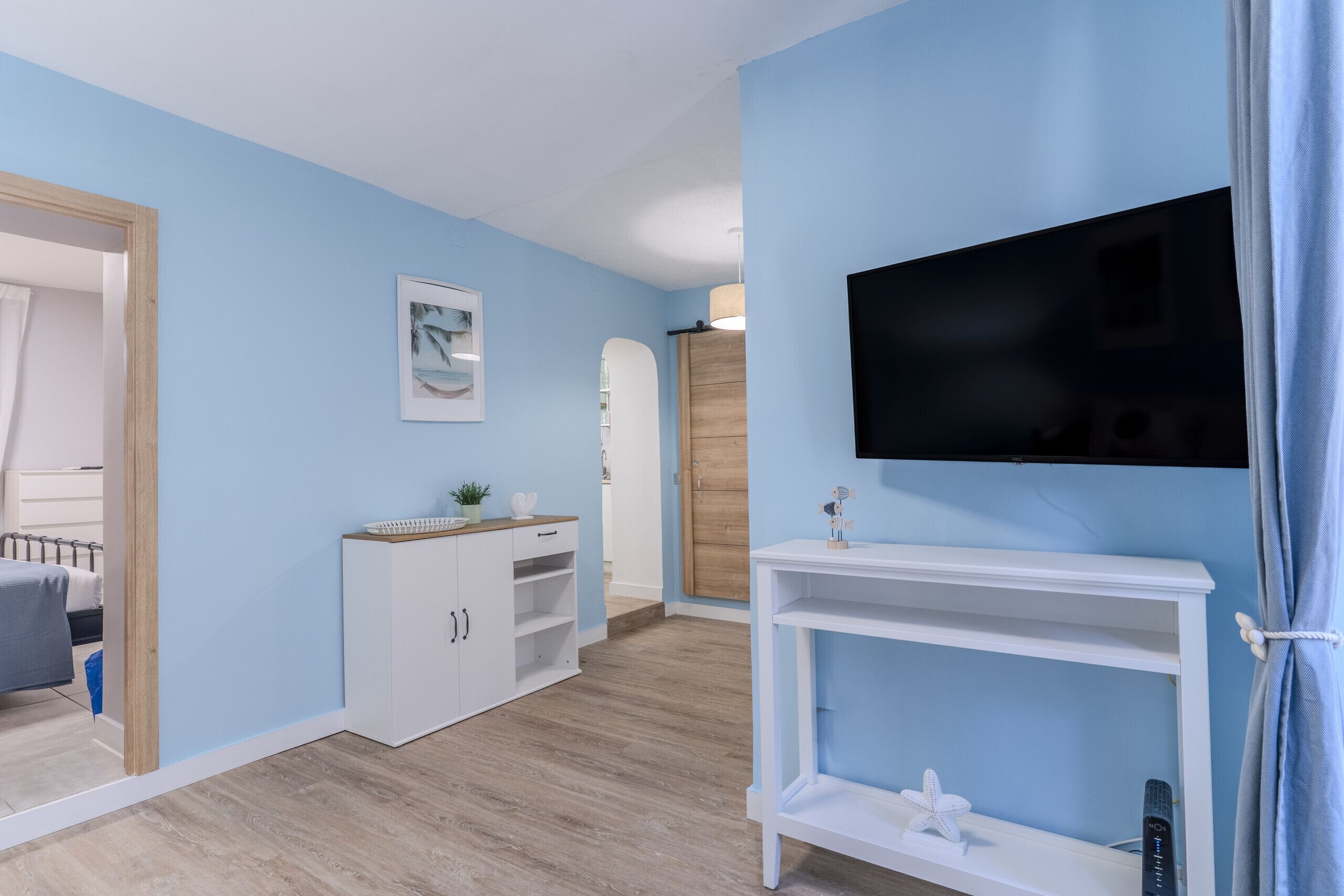 Una habitación con una cama, televisión, armario y puerta que da a otra estancia.