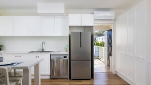 Una cucina moderna con mobili bianchi, elettrodomestici in acciaio inossidabile e un'area pranzo con tavolo e sedie.