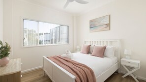 A bedroom with a bed, bedside tables, a window, and a painting on the wall. - Sotto  Shoal Bay Walk to Shoal Bay Beach (Shoal Bay)