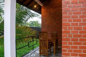 Ein Balkon mit Backsteinmauer, einem Holzstuhl und einem Metallgeländer.