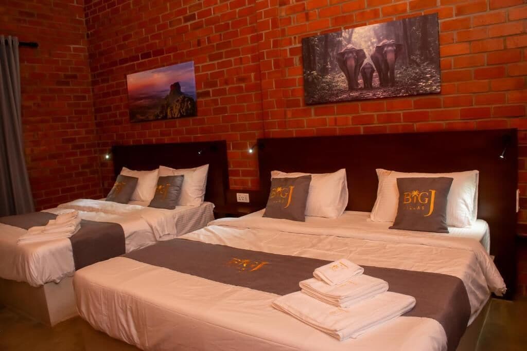 Quarto de hotel com duas camas, parede de tijolos e obras de arte.