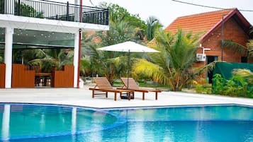 Una piscina al aire libre, sombrillas, sillones reclinables de piscina