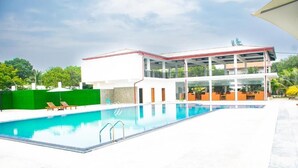 Een modern gebouw met een zwembad, een overdekt buitengedeelte en een groene omheining.