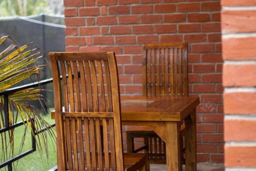 A wooden table and chairs set against a brick wall.