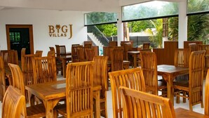 Un restaurant doté de meubles en bois, d’un escalier et offrant une vue sur la verdure.