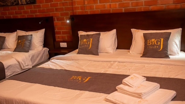 Een hotelkamer met twee bedden, elk voorzien van bijpassende kussens en een loper met het logo van het hotel.