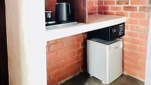 A compact kitchen with a brick wall, a white countertop, and a small white refrigerator.