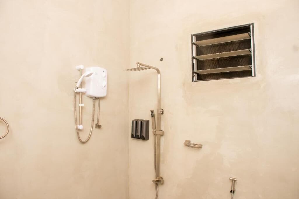 Casa de banho com chuveiro, sanita e secador de mãos.