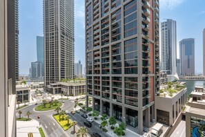 A high-rise building with multiple floors, surrounded by other tall buildings, a road with vehicles, and a body of water in the background. - Refined Studio with Sweeping Dubai Water Canal and City Views (Dubai)