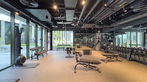 A modern gym with various exercise equipment, large windows, and a clean, well-lit interior. - Refined Studio with Sweeping Dubai Water Canal and City Views (Dubai)