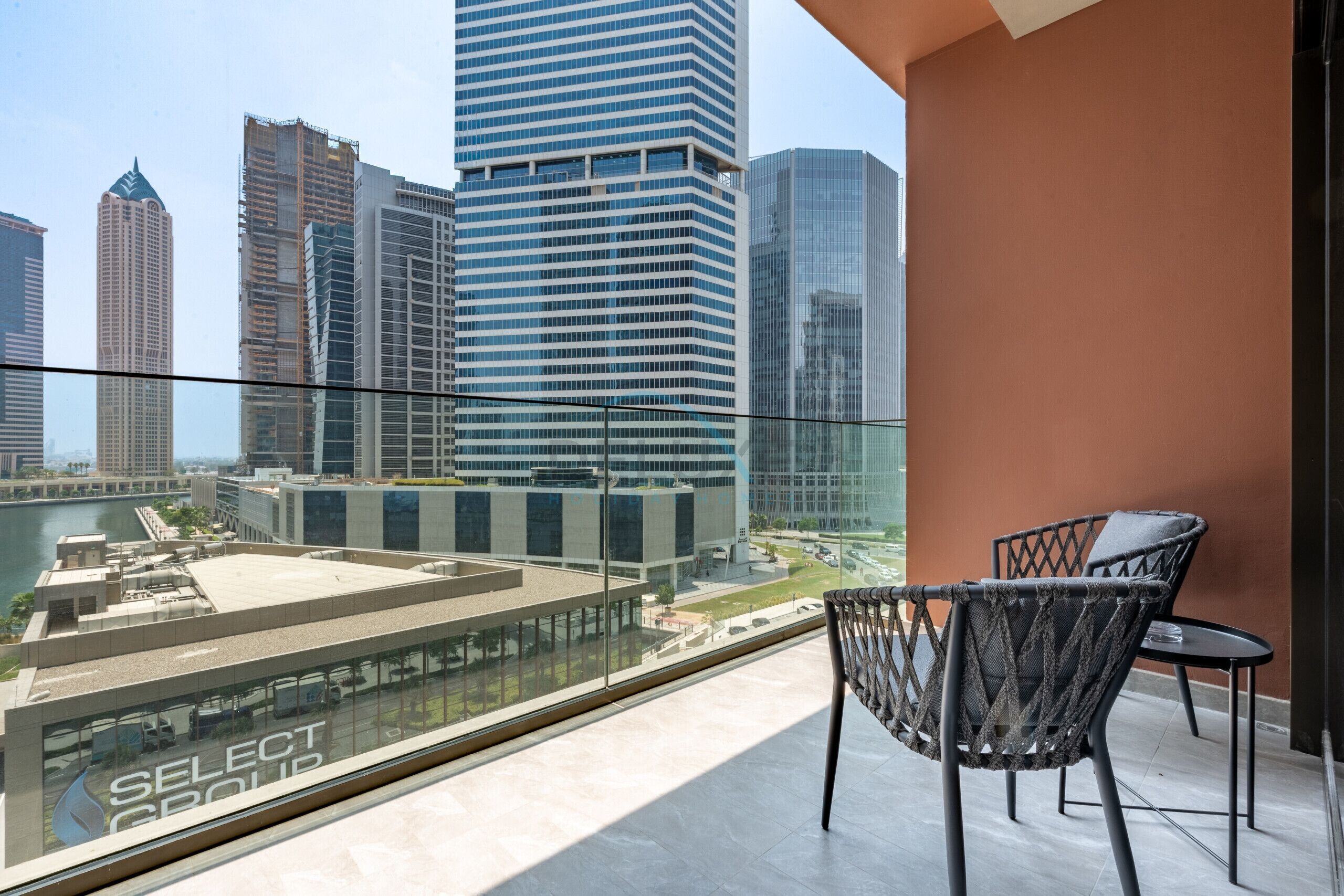 Un balcon offrant une vue sur le paysage urbain, avec notamment des immeubles de grande hauteur et un hôtel appelé «SELECT GROUP».