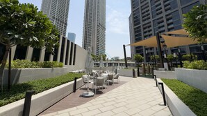 A rooftop terrace with outdoor seating and a view of tall buildings. - Refined Studio with Sweeping Dubai Water Canal and City Views (Dubai)