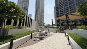 A rooftop terrace with outdoor seating and a view of tall buildings. - Refined Studio with Sweeping Dubai Water Canal and City Views (Dubai)