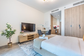 A modern hotel room with a large bed, a TV, a desk, and a kitchenette. - Refined Studio with Sweeping Dubai Water Canal and City Views (Dubai)