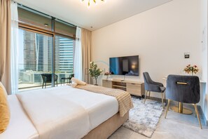 A modern hotel room with a large bed, a desk, a television, and a view of the cityscape. - Refined Studio with Sweeping Dubai Water Canal and City Views (Dubai)