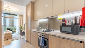 A modern kitchen with a built-in oven, a microwave, and a coffee maker. - Refined Studio with Sweeping Dubai Water Canal and City Views (Dubai)