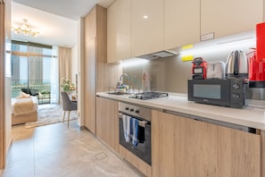 A modern kitchen with a built-in oven, a microwave, and a coffee maker. - Refined Studio with Sweeping Dubai Water Canal and City Views (Dubai)
