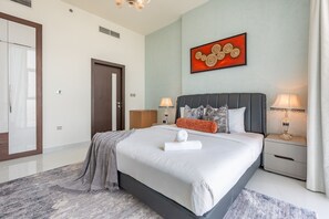Ein Hotelzimmer mit einem großen Bett, zwei Nachttischlampen, einem Gemälde an der Wand und einer Tür.