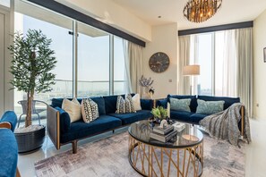 Ein modernes Wohnzimmer mit einem blauen Sofa, einem runden Couchtisch und einem großen Fenster mit Blick auf die Stadt.