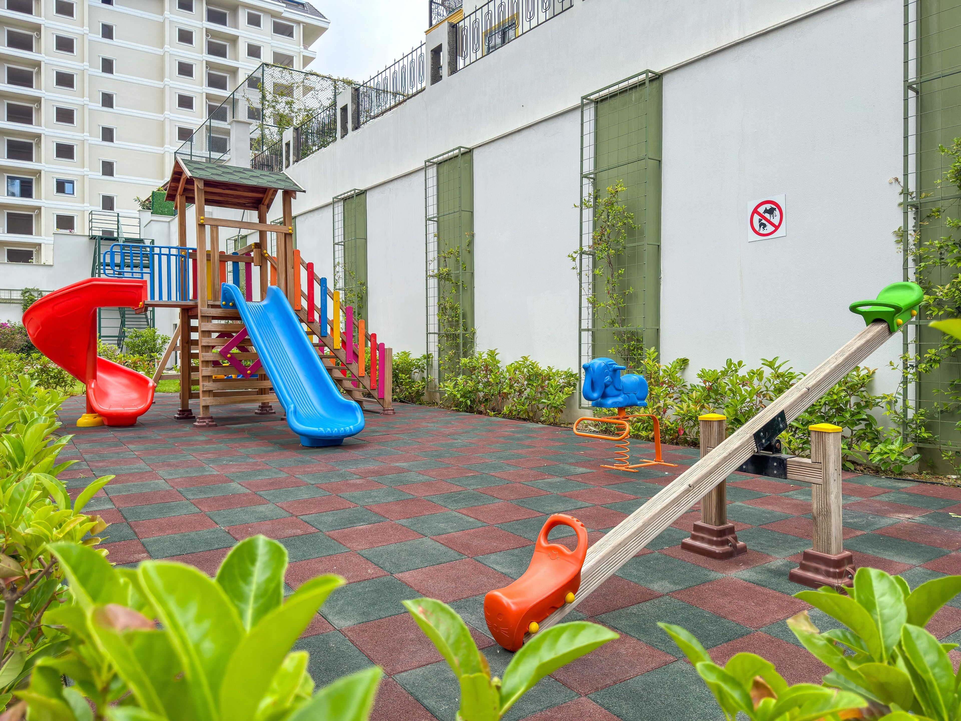 Un espace de jeux pour enfants avec un toboggan, une structure d’escalade et une balançoire.
