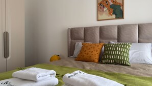 A neatly made bed with a green blanket, white towels, and two pillows with distinct patterns. - Qoople Green Ocean A49 - Cozy 1-bedroom apartment in Alanya (Alanya)
