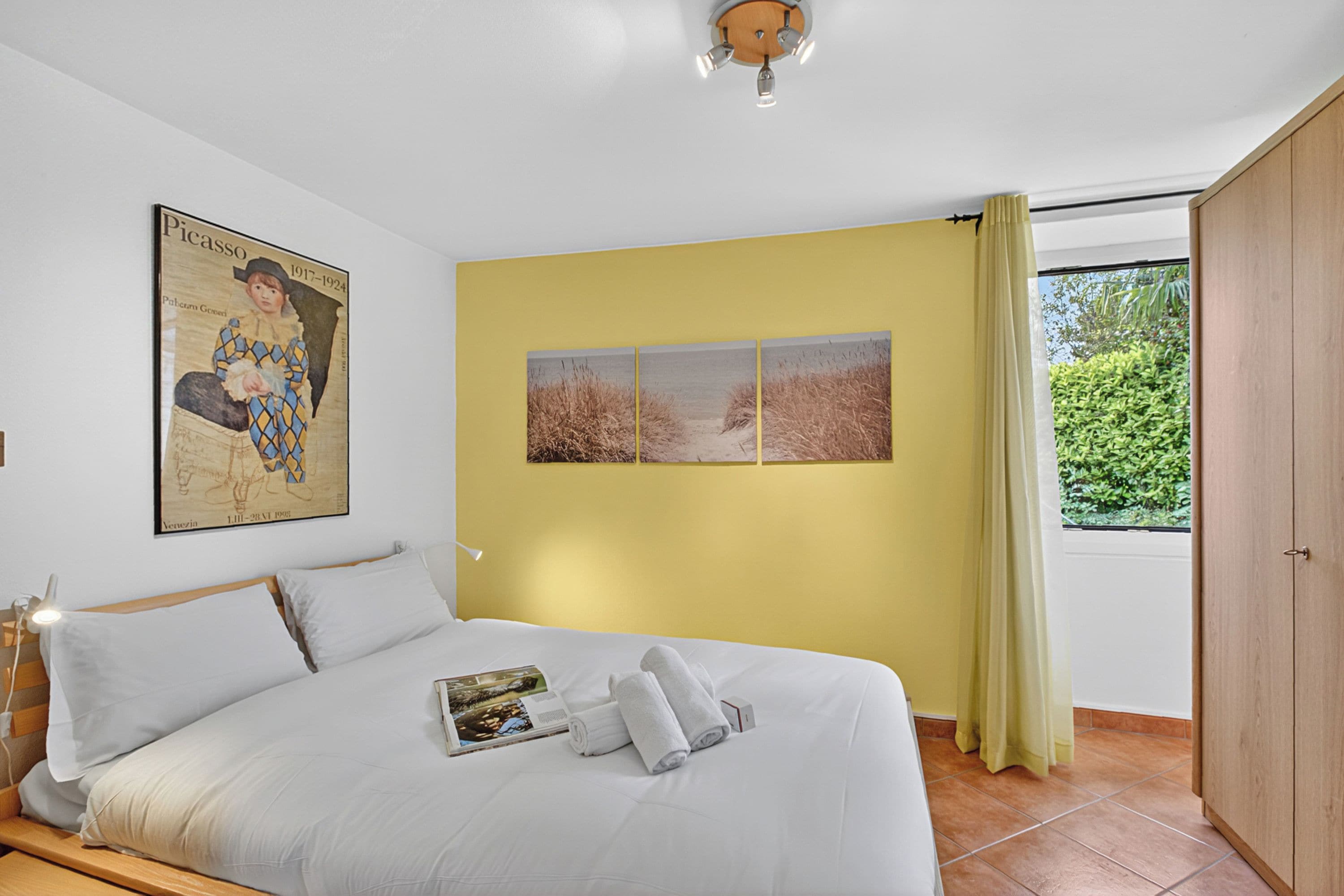 Une chambre à coucher avec un lit, une affiche et trois photographies de paysages accrochées au mur.