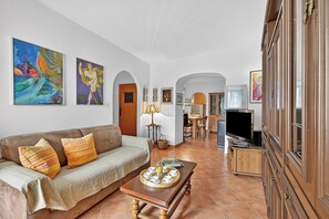 Ein Wohnzimmer mit Sofa, Couchtisch, Fernseher und Kunstwerken an den Wänden.