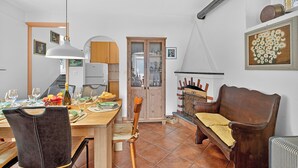 Ein Essbereich mit einem Holztisch, gedeckt für vier Personen, einer Holzbank und einem Schrank mit Glastüren.