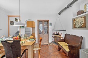 Ein Essbereich mit einem Holztisch, gedeckt für vier Personen, einer Holzbank und einem Schrank mit Glastüren.