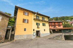 A yellow building with a balcony, a stone staircase, and a small door. - Casa Berta Brissago 2 With Balcony for Six (Brissago)
