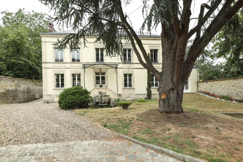 Un edificio de dos pisos con fachada simétrica, una entrada central y un camino de piedra que conduce a ella.