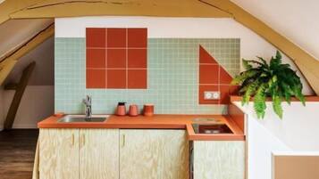 Cozinha com teto inclinado, vigas de madeira e painel de azulejos.