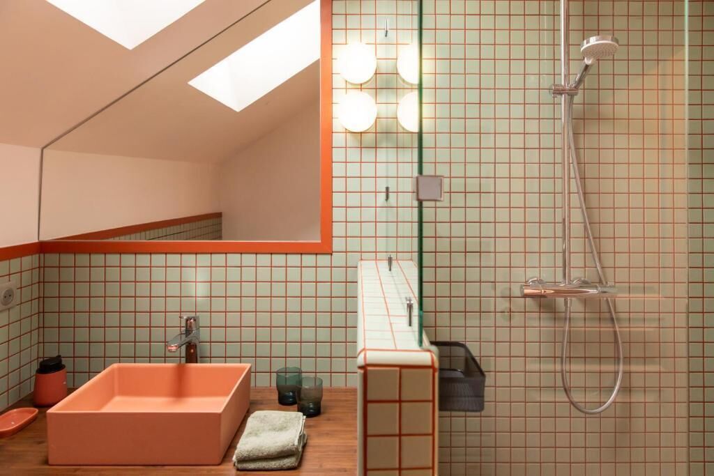 Een moderne badkamer met een grote spiegel, een rechthoekig wastafelmeubel, een douche en een dakraam.