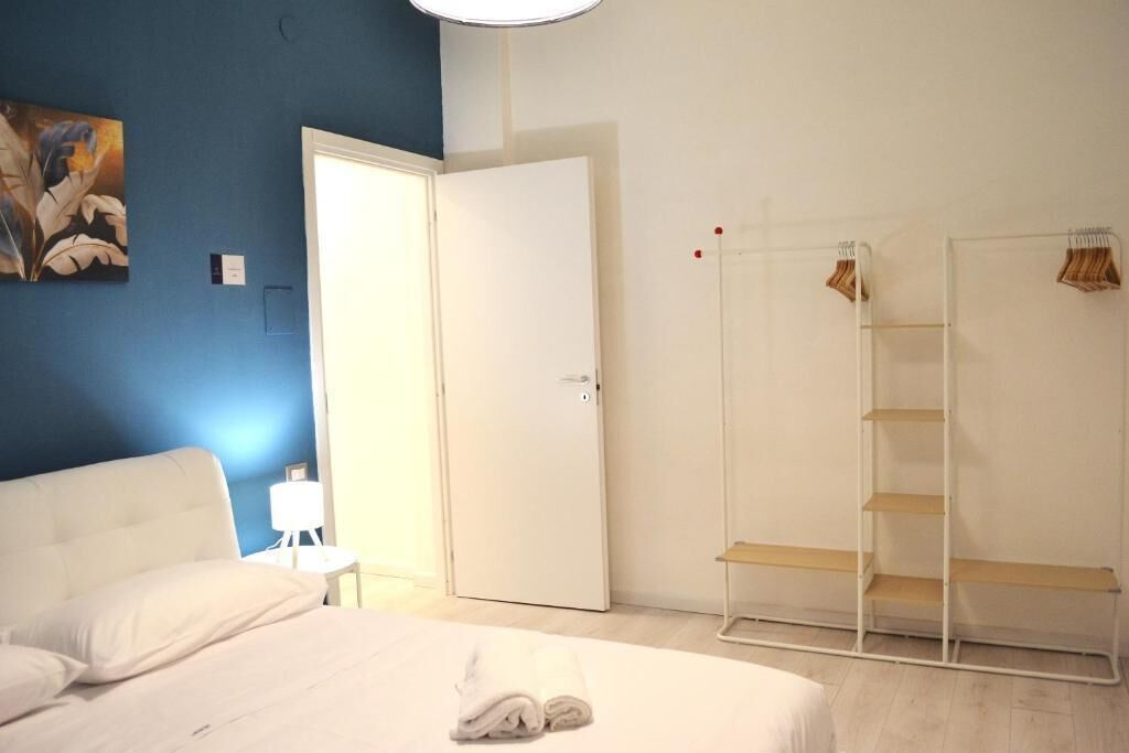 Habitación de hotel con cama, armario, mesita de noche y un cuadro en la pared.