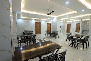 A modern dining area with marble walls, wooden doors, and ceiling fans. - Hill View Haridwar Run by R.K. Group (Haridwar)
