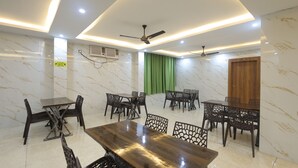 Un espace de restauration moderne avec des murs en marbre, des ventilateurs de plafond et un rideau vert.