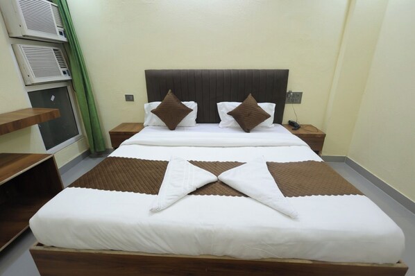 A neatly made bed with a brown and white bedspread, two pillows, and a headboard. - Hill View Haridwar Run by R.K. Group (Haridwar)