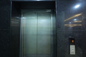 Een lift met een digitaal scherm dat '0' toont en een knop met de tekst 'Boston'.