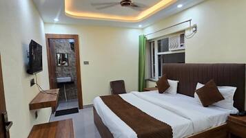 A modern hotel room with a large bed, a desk, a mirror, and a ceiling fan.