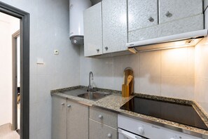 A kitchen with a built-in sink, a stove, cabinets, and a water heater. - Apartment next to Salou's Ponent Beach (Salou)