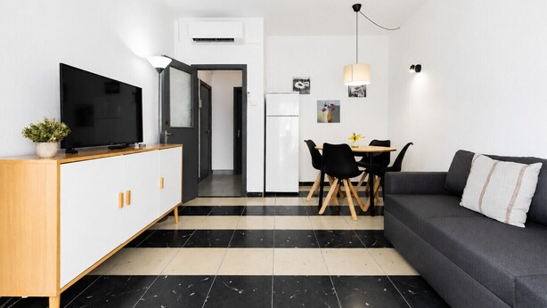 Un espace de vie moderne comprenant un canapé, un téléviseur, une table à manger et un coin cuisine.