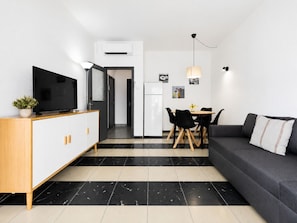A modern living space with a sofa, TV, dining table, and kitchen area. - Apartment next to Salou's Ponent Beach (Salou)