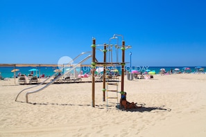 Ein Spielplatz am Strand mit Rutsche und Klettergerüst.