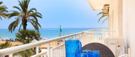 Un balcón con vista a la playa, palmeras y una barandilla.